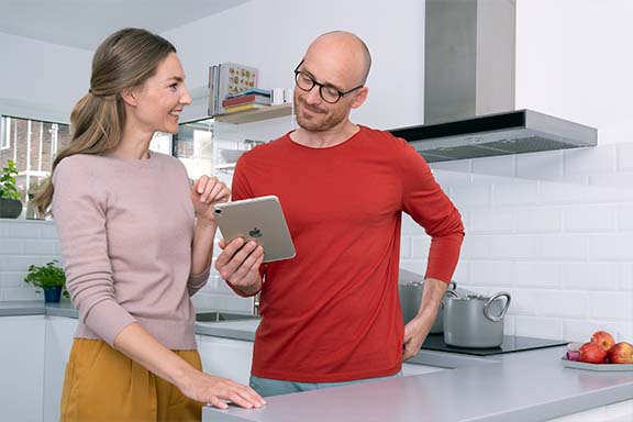 Personen stehen in der Küche und schauen auf ein iPad.